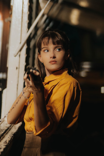 image of a girl wearing a second-hand outfit holding an old-fashioned phone outside in a park