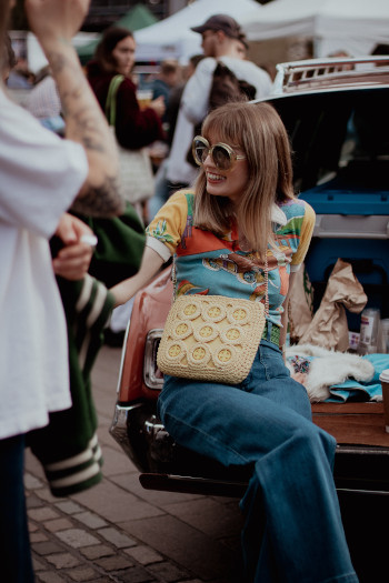 image of a young girl looking down sitting on grass wearing a second-hand outfit